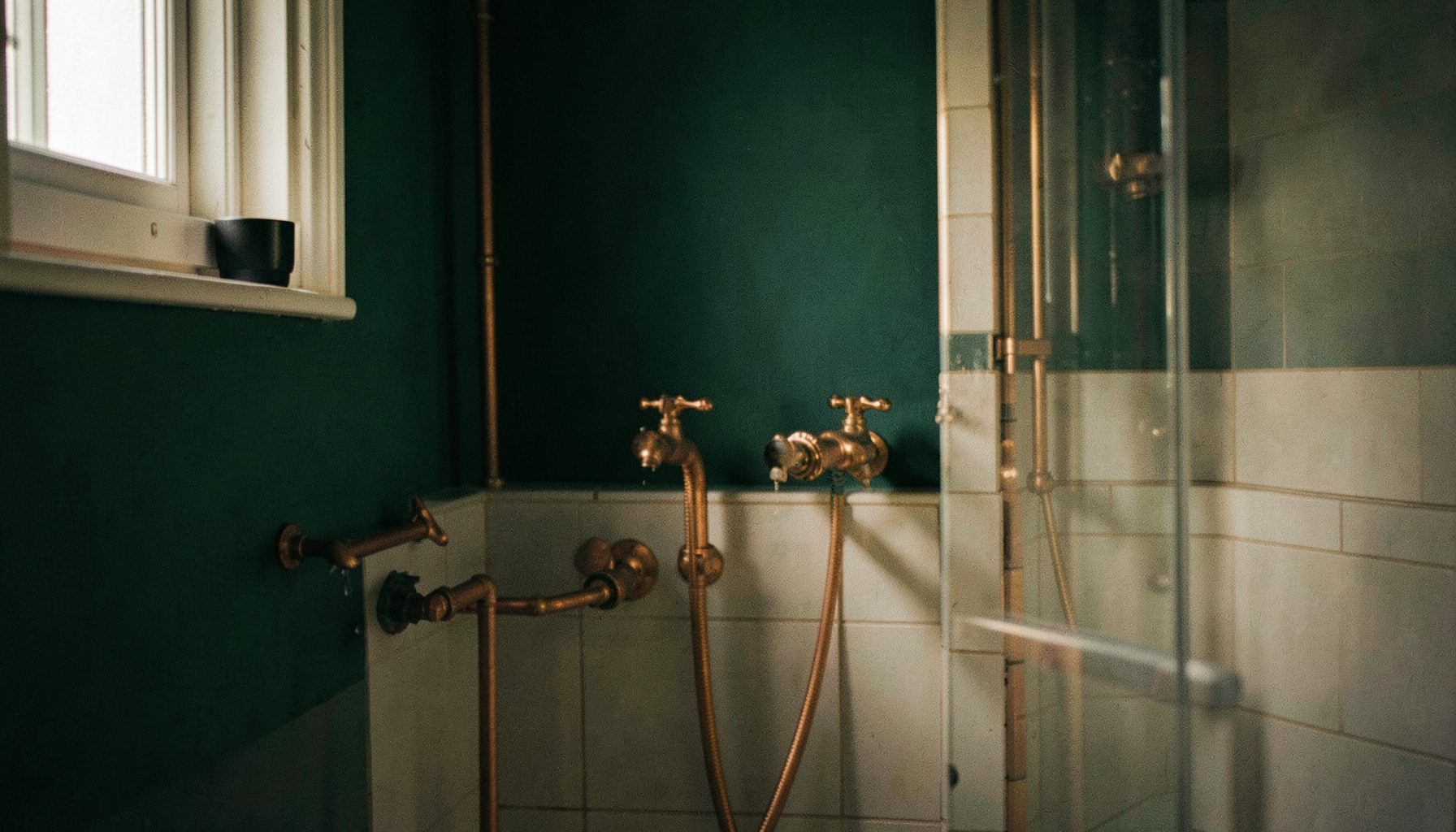 Warm residential bathroom with copper plumbing fixtures and deep green accent wall